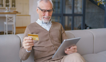 Ein Senior beim entspannten Online-Banking mit Tablet und Kreditkarte