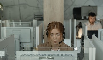 Frau mit Headset sitzt an einem Computer in der Notrufzentrale