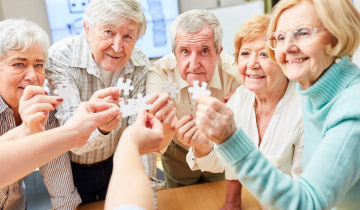 Eine Gruppe älterer Menschen hält fröhlich Puzzle-Teile in die Höhe