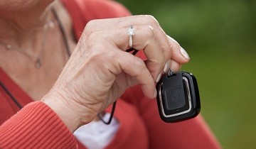 Ältere Frau hält Hausnotruf-Armband in der Hand