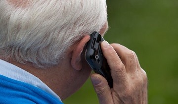 Mann mit grauem Haar hält HelpPhone-Mobiltelefon an sein Ohr